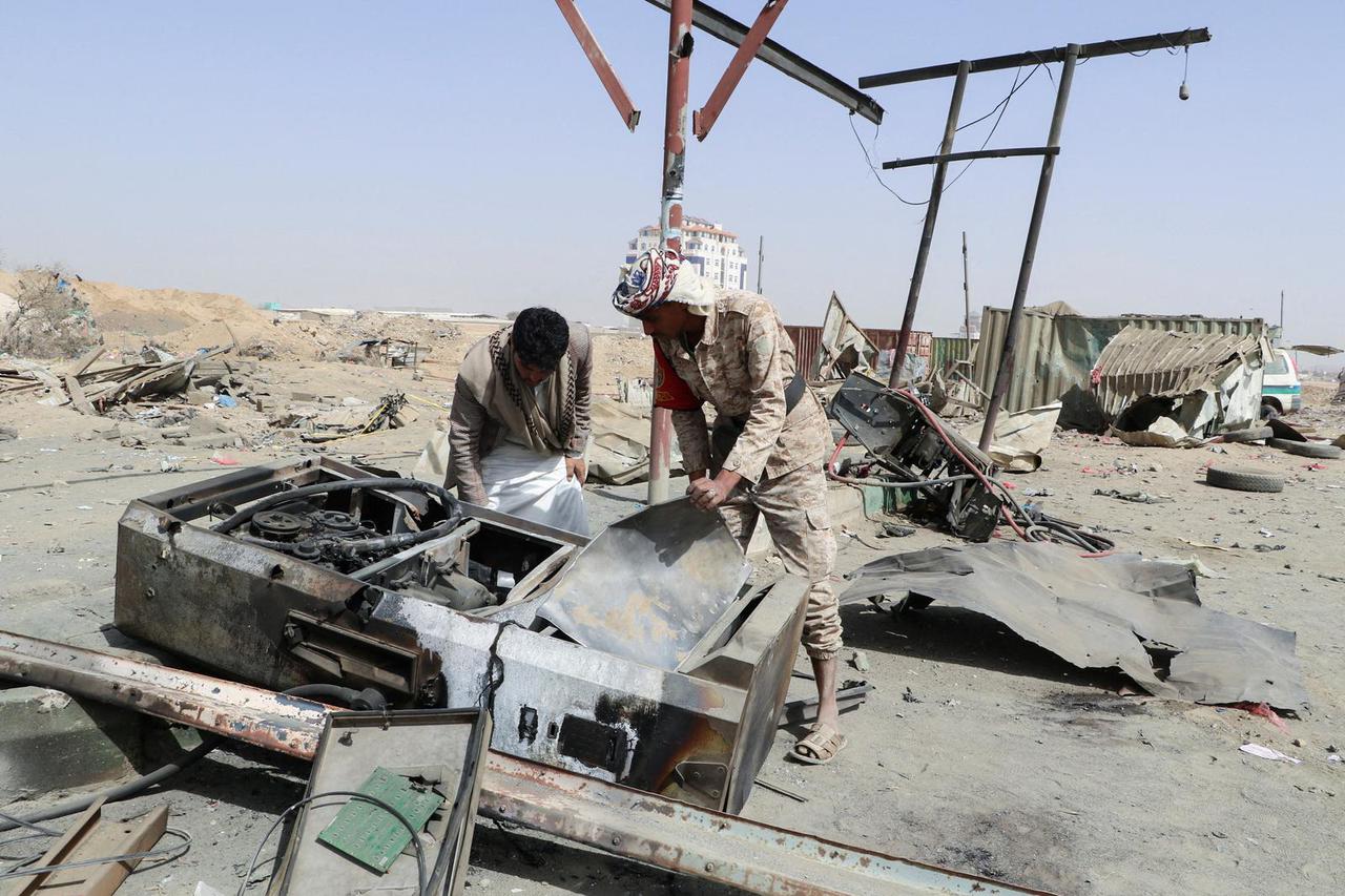 Man and a soldier inspect damage at a gas station hit by a Saudi-led air strike, in Saada