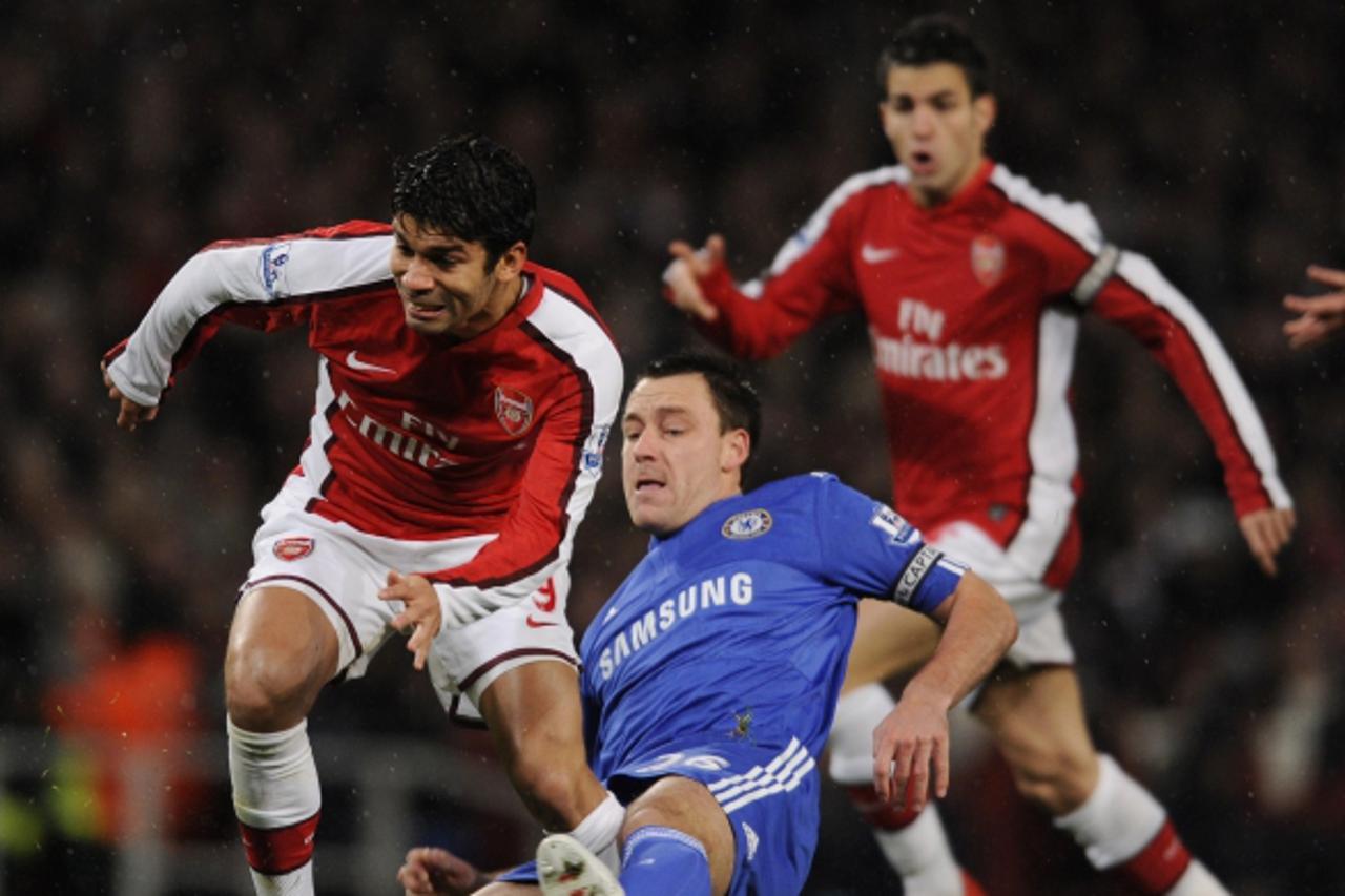 'Chelsea\'s John Terry (C) gets a tackle in on Arsenal\'s Brazilian forward Eduardo (L) during the Premiership match at the Emirates Stadium in London on November 29, 2009. AFP PHOTO / Adrian Dennis  