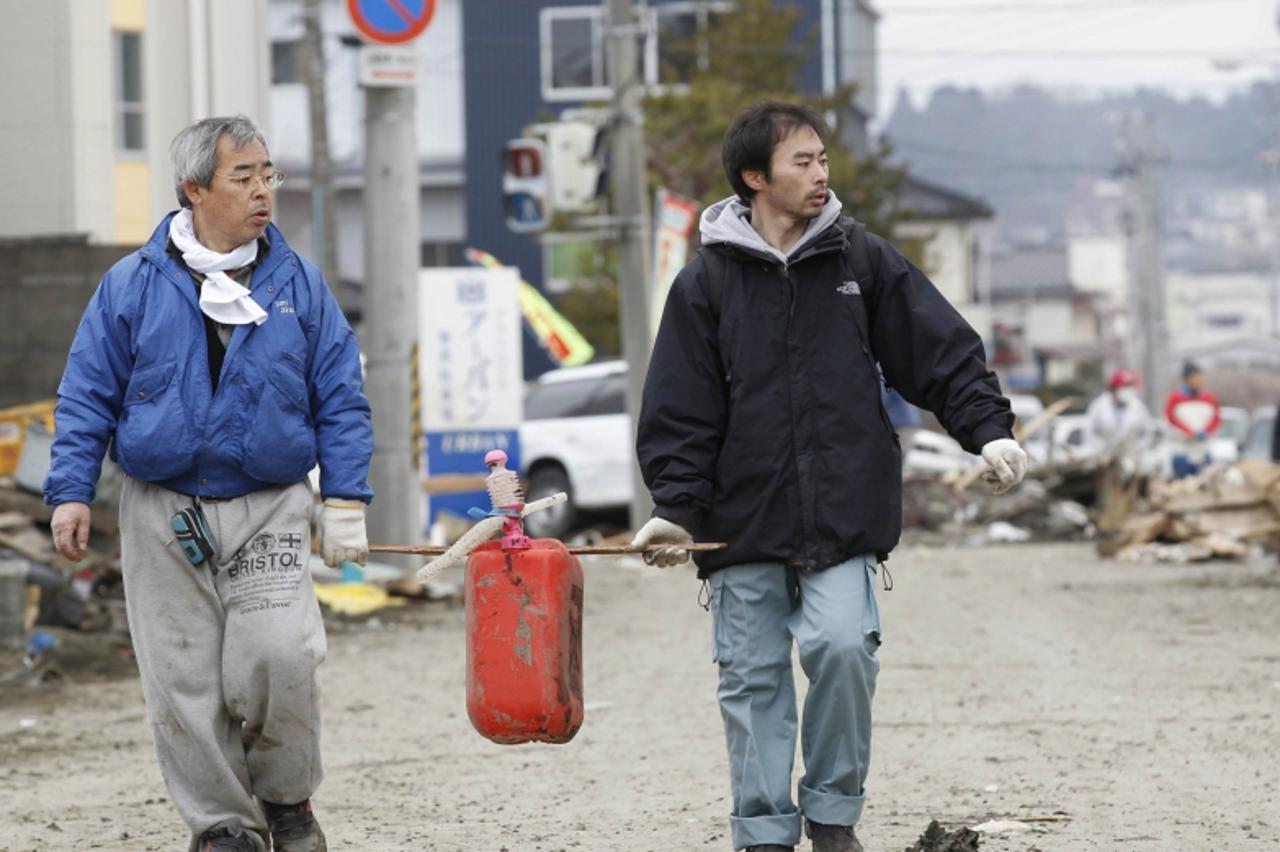 \'Men carry fuel at devastated area hit by earthquake and tsunami in Kesennuma, Miyagi Prefecture in northern Japan, March 15, 2011.   REUTERS/Kim Kyung-Hoon (JAPAN - Tags: DISASTER ENVIRONMENT)\'