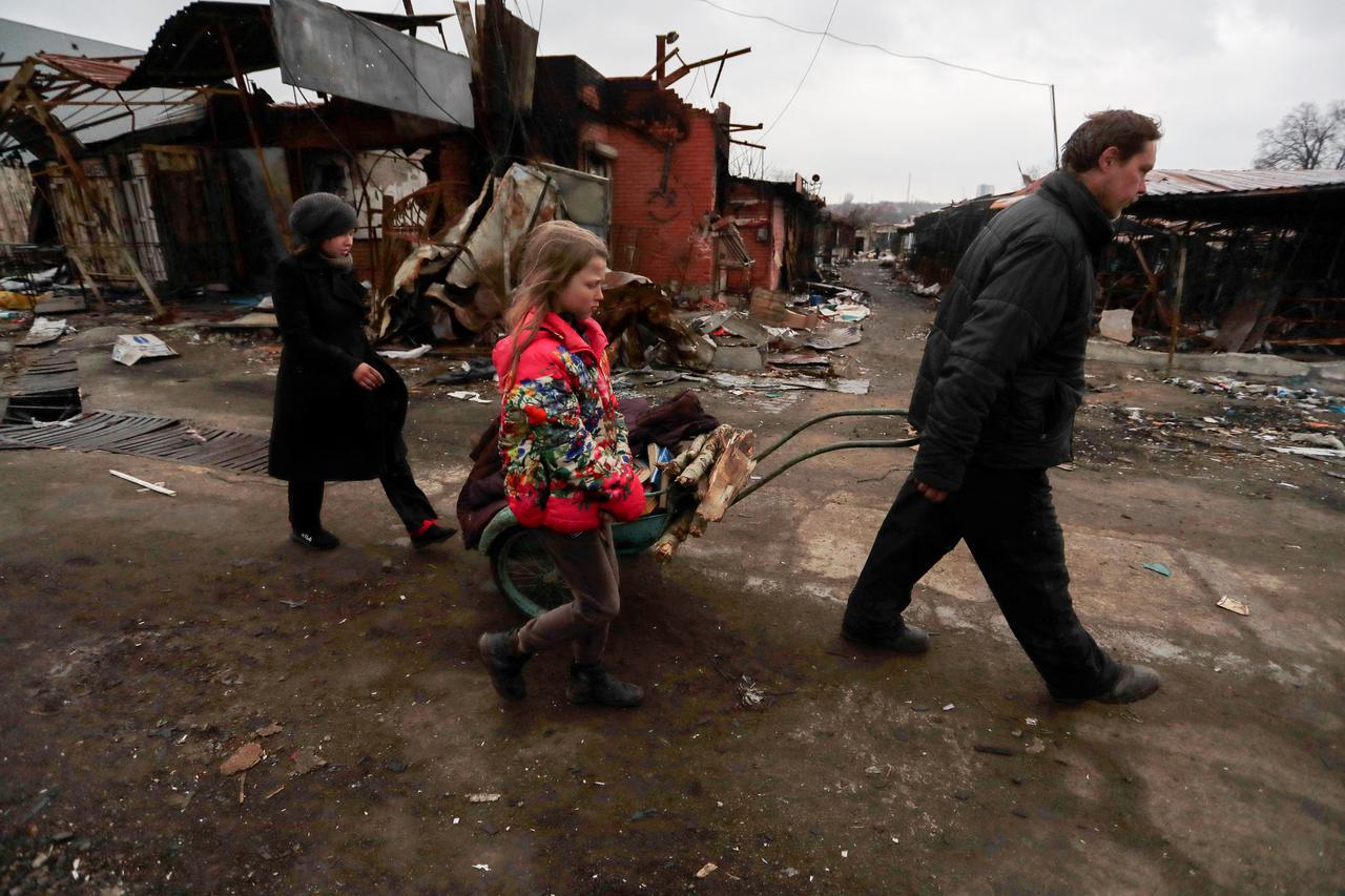 People walk past damaged buildings in Mariupol