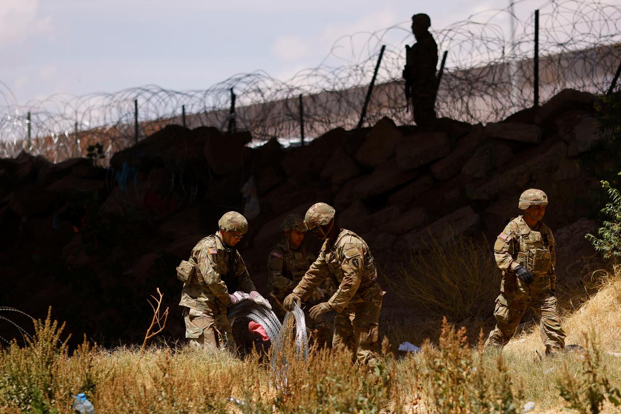 Members of the Texas Army National Guard extend razor wire to inhibit migrants from crossing, as seen from Ciudad Juarez