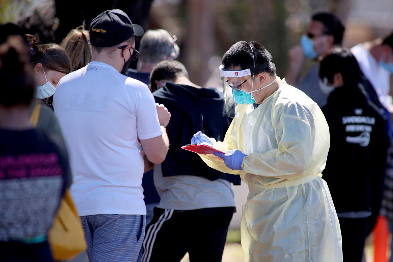 A medical staff member takes details from people queuing at a COVID-19 testing site in Adelaide