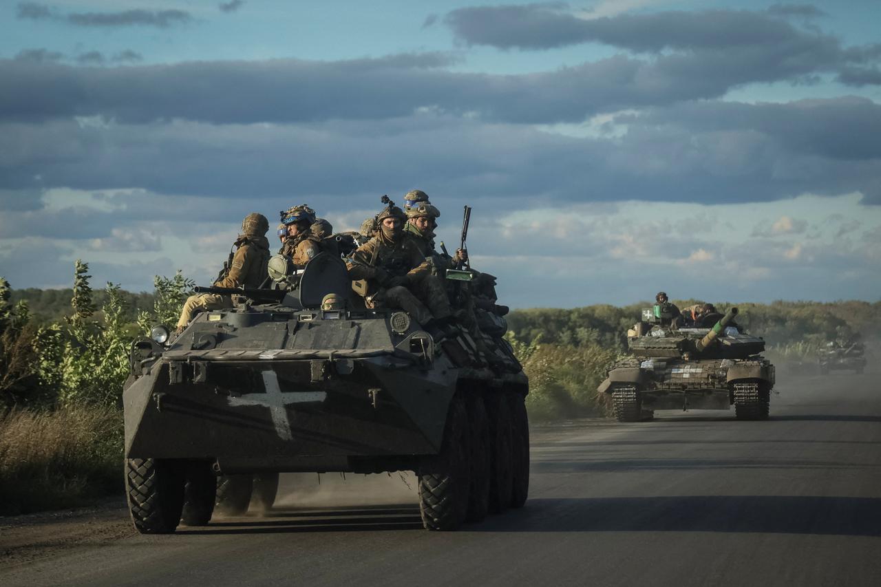 Ukrainian servicemen ride on Armoured Personnel Carrier (APC) and a tank in the town of Izium