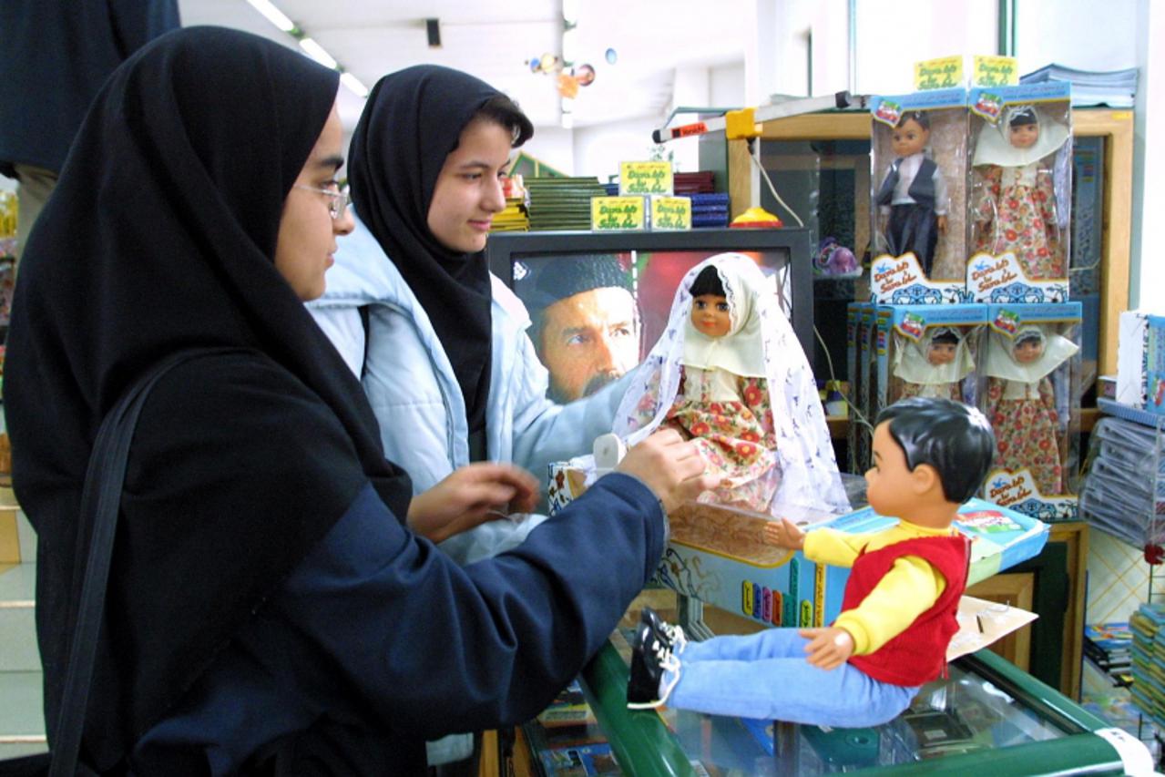 'Iranian girls check out locally-made dolls, Sara (L) and Dara (R), at a toy shop in Tehran 17 March 2002. Iran released its twin national dolls on the market recently with Sara dressed in traditional
