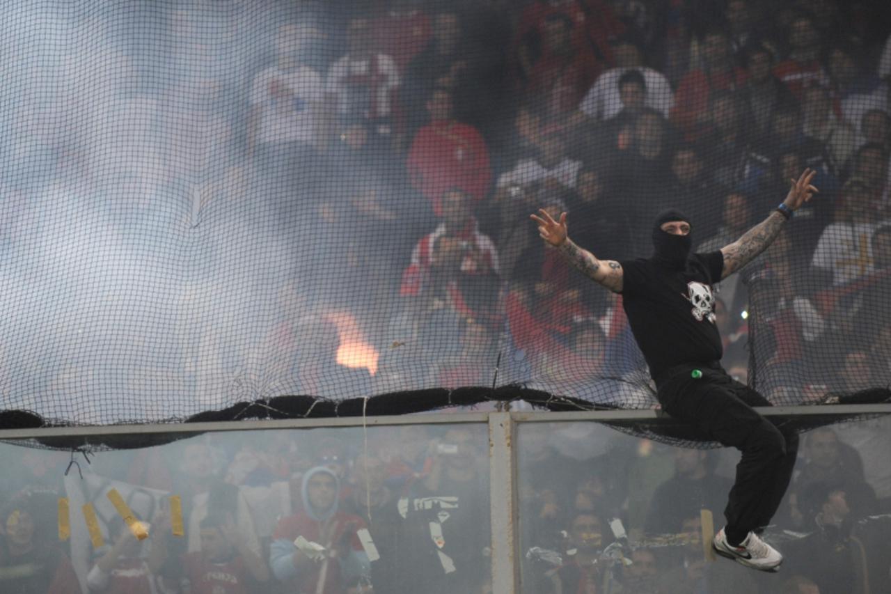 'A Serbian fan sits on a protection glass during the Italy-Serbia football Euro 2012 Group C qualifier on October 12, 2010 in Genova. The game was suspended following crowd trouble.  AFP PHOTO / GIUSE