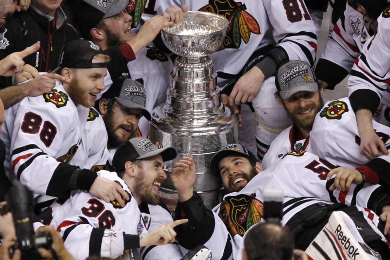 'Chicago Blackhawks\' Patrick Kane (L), Dave Bolland (C) and goalie Corey Crawford (R) celebrate with the Stanley Cup after they defeated the Boston Bruins in Game 6 of their NHL Stanley Cup Finals ho