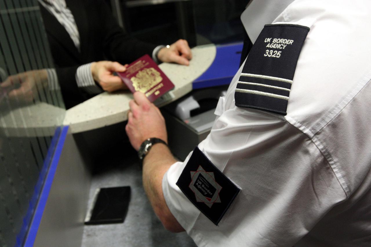 A UK Border Agency officer checks a passport in the North Terminal of Gatwick Airport, Sussex.  Photo: Press Association/PIXSELL