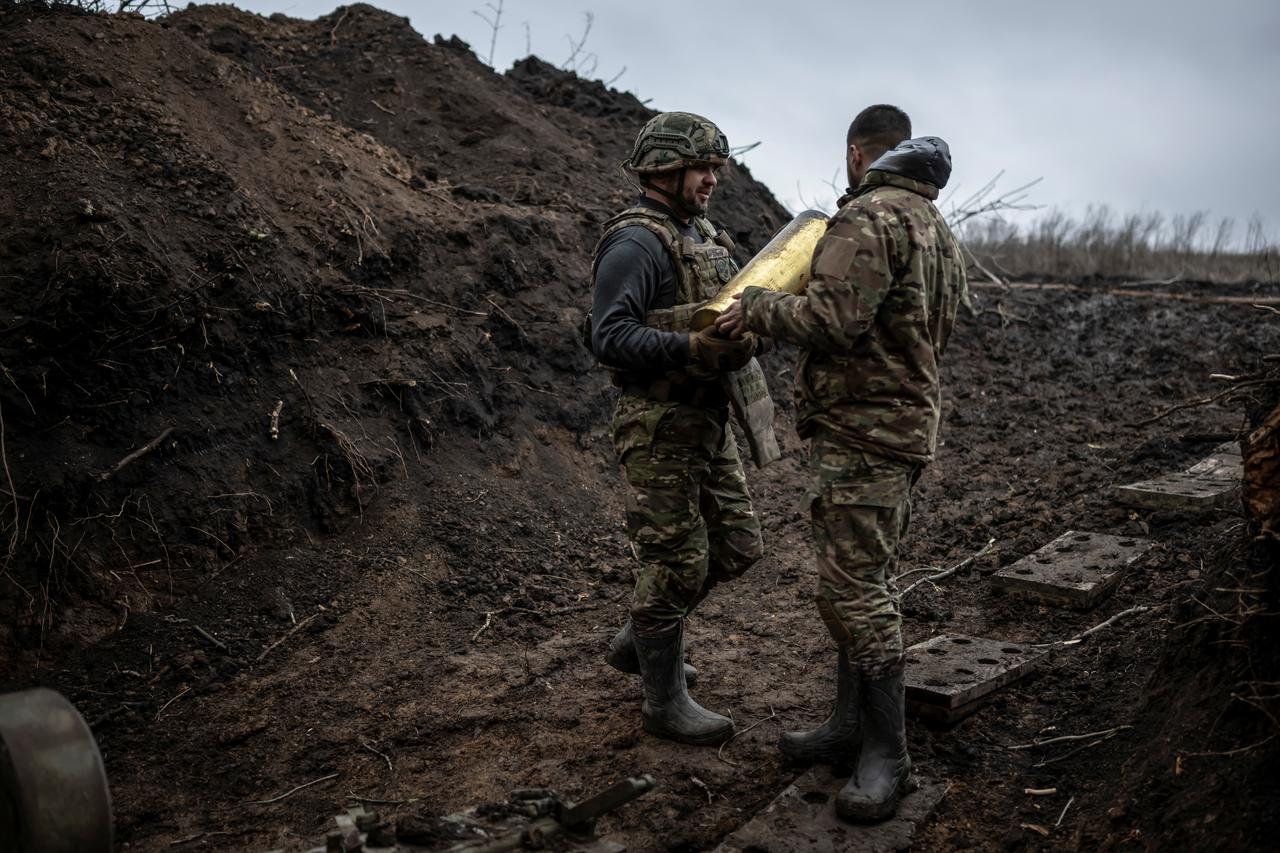 Ukrainian servicemen hold a howitzer shell at a position near the front line town of Bakhmut