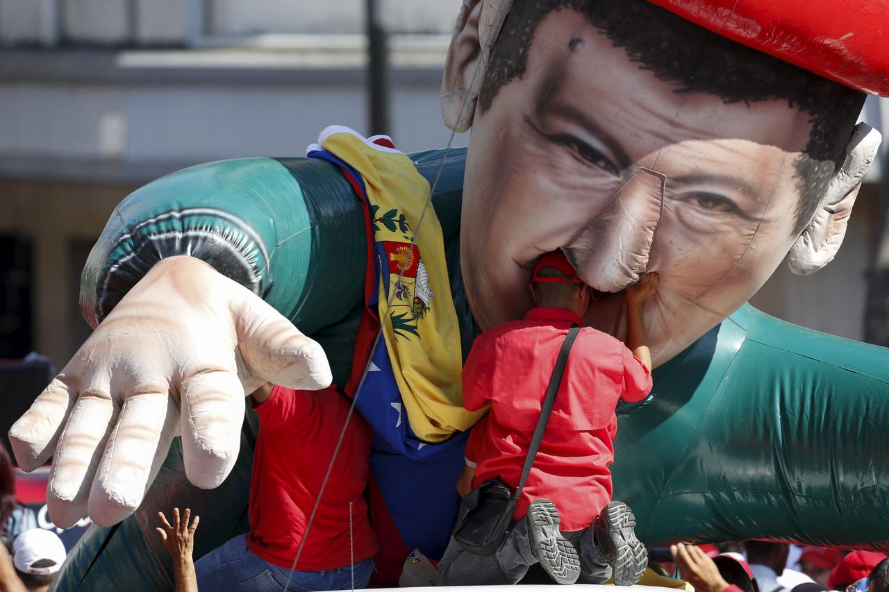 A worker of the Venezuelan state oil company PDVSA tries to attach the national flag to a giant inflatable figure of Venezuela's late President Hugo Chavez, during a meeting with Venezuela's President Nicolas Maduro outside Miraflores Palace in Caracas Ja