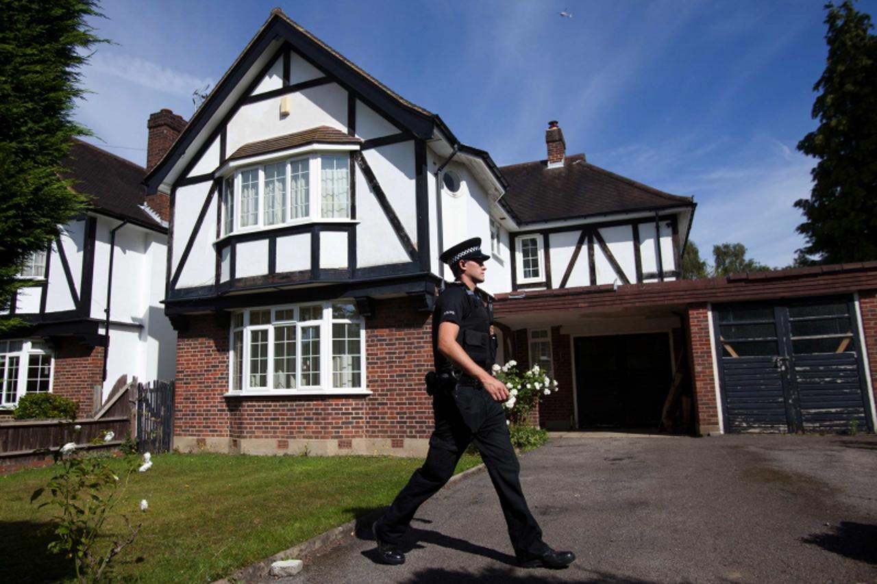 'A police officer walks in the grounds of the home of Saad al-Hilli in Claygate, south of London September 6, 2012. French police have found a girl aged about 4 alive in a car with the dead bodies of 