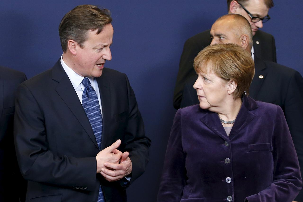 Britain's Prime Minister David Cameron talks to Germany's Chancellor Angela Merkel (R) as they leave a family photo during a European Union leaders summit in Brussels, December 17, 2015. EU leaders are due to discuss on the migrant crisis and Cameron's de