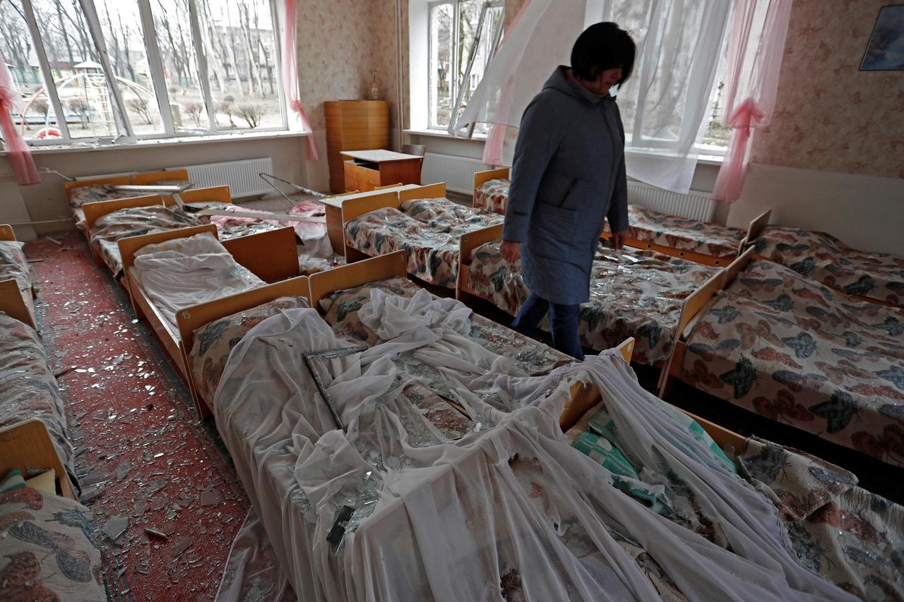 A teacher walks through a bedroom at a damaged kindergarten in Donetsk