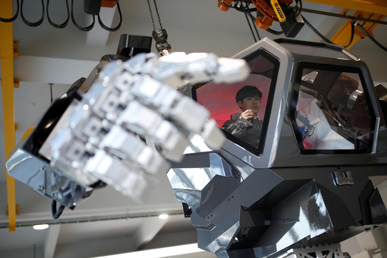 An employee controls the arms of a manned biped walking robot 