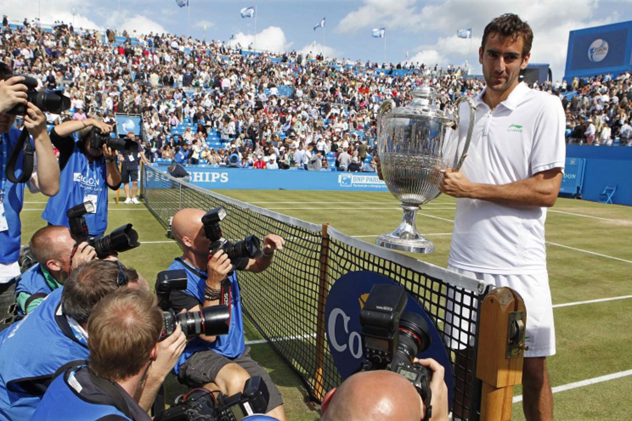 'Marin Cilic of Croatia holds his trophy after winning his men\'s singles final match against David Nalbandian of Argentina, who lost by default at the Queen\'s Club tennis tournament in London June 1