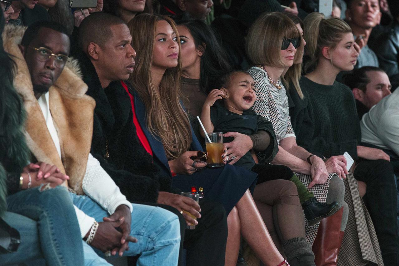Kim Kardashian attempts to calm her daughter, North, while sitting next to Sean Combs (L), Jay-Z (2nd L), Beyonce (3rd L) and Anna Wintour (2nd R) as they watch a presentation of Kanye West's Fall/Winter 2015 partnership with Adidas at New York Fashion We
