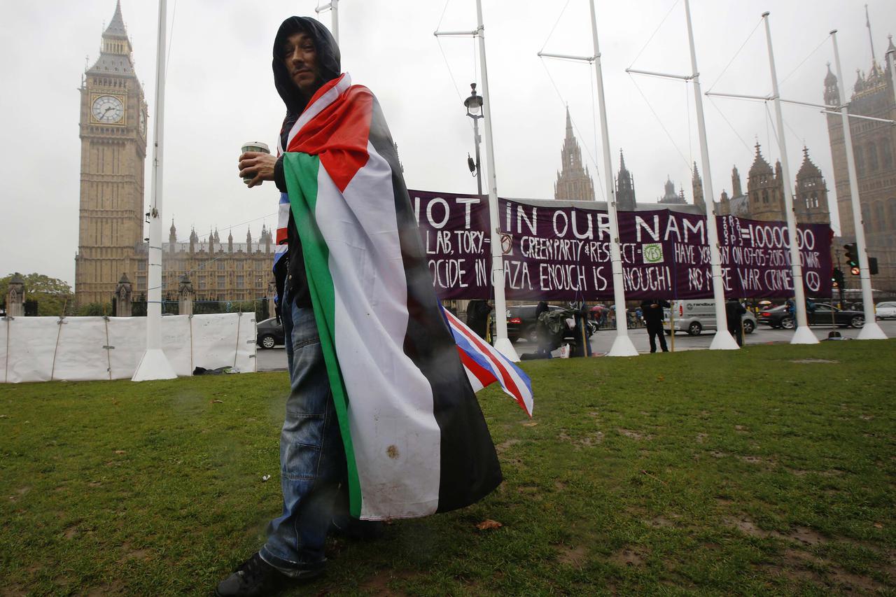 A pro-Palestine supporter wears a Palestinian and Union flag outside the Houses of Parliament in London October 13, 2014.  British Prime Minister David Cameron will not take part in a parliamentary vote on whether the government should recognise Palestine