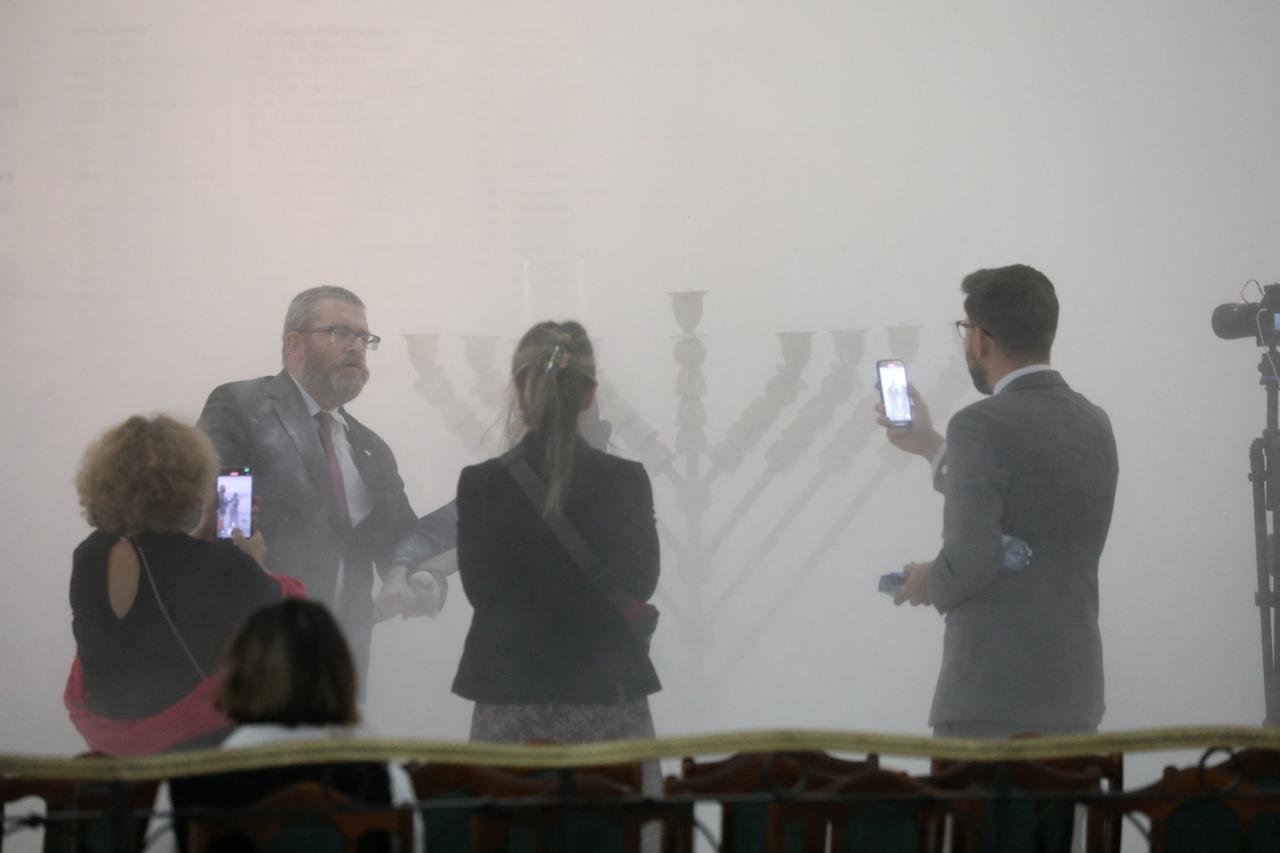 Far-right Polish lawmaker Grzegorz Braun from Konfederacja party stands after using a fire extinguisher to put out Hanukkah candles at the parliament in Warsaw