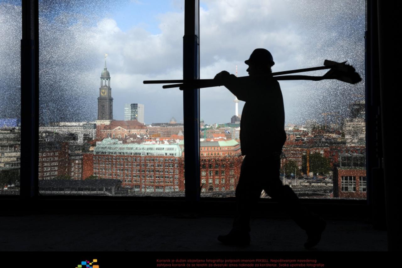 \'(dpa file) - A file picture dated 20 October 2010 shows a construction worker walking past a special window of the construction site of the Elbphilharmonie concert hall in Hamburg, Germany. A buildi