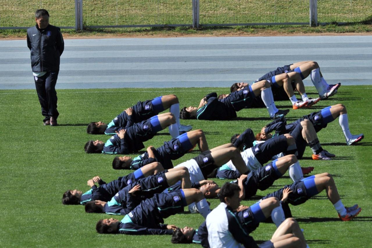 'South Korean national football team head coach Huh Jung-Moo look on as his players stretch (L) during a training session at the Olympia Park Stadium in Rustenburg on June 6, 2010 ahead of the start o