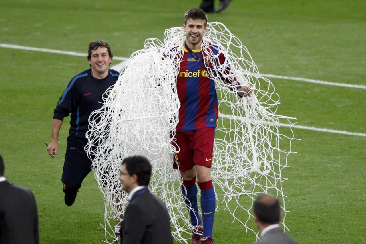 \'Barcelona\'s Gerard Pique holds the net from the goal as he celebrates after their Champions League final soccer match against Manchester United at Wembley Stadium in London May 28, 2011. REUTERS/Pa
