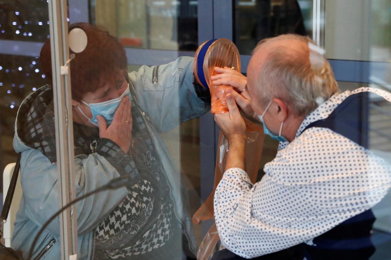Agnes Javor, 58, cries as she interacts with her husband Peter Szilagyi, 59, behind a plexiglass wall which allows families to give hugs without risk of contamination or transmission of COVID-19 in Budapest