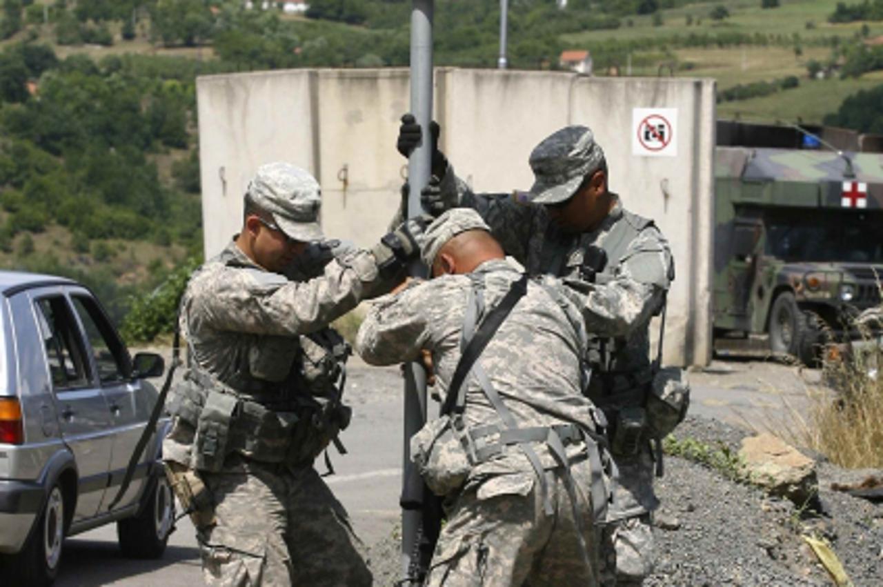 \'U.S. NATO soldiers repair a road sign near the Serbia-Kosovo border crossing in Jarinje July 28, 2011. A deadly flare-up of violence in Kosovo\'s Serbian-populated north has sent tensions with Belgr