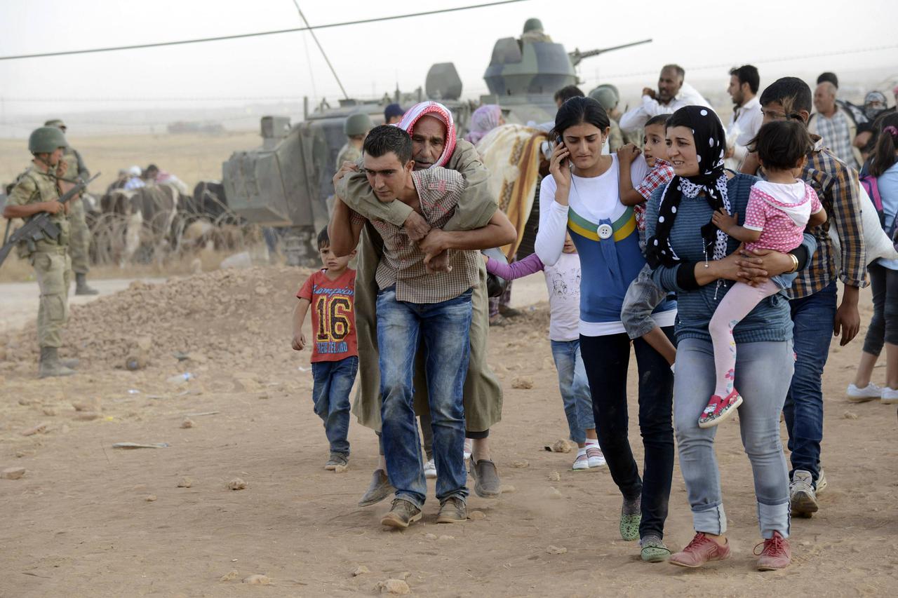 Syrian Kurds walk after crossing into Turkey at the Turkish-Syrian border, near the southeastern town of Suruc in Sanliurfa province, September 20, 2014. About 60,000 Syrian Kurds fled into Turkey in the space of 24 hours, a deputy prime minister said on 