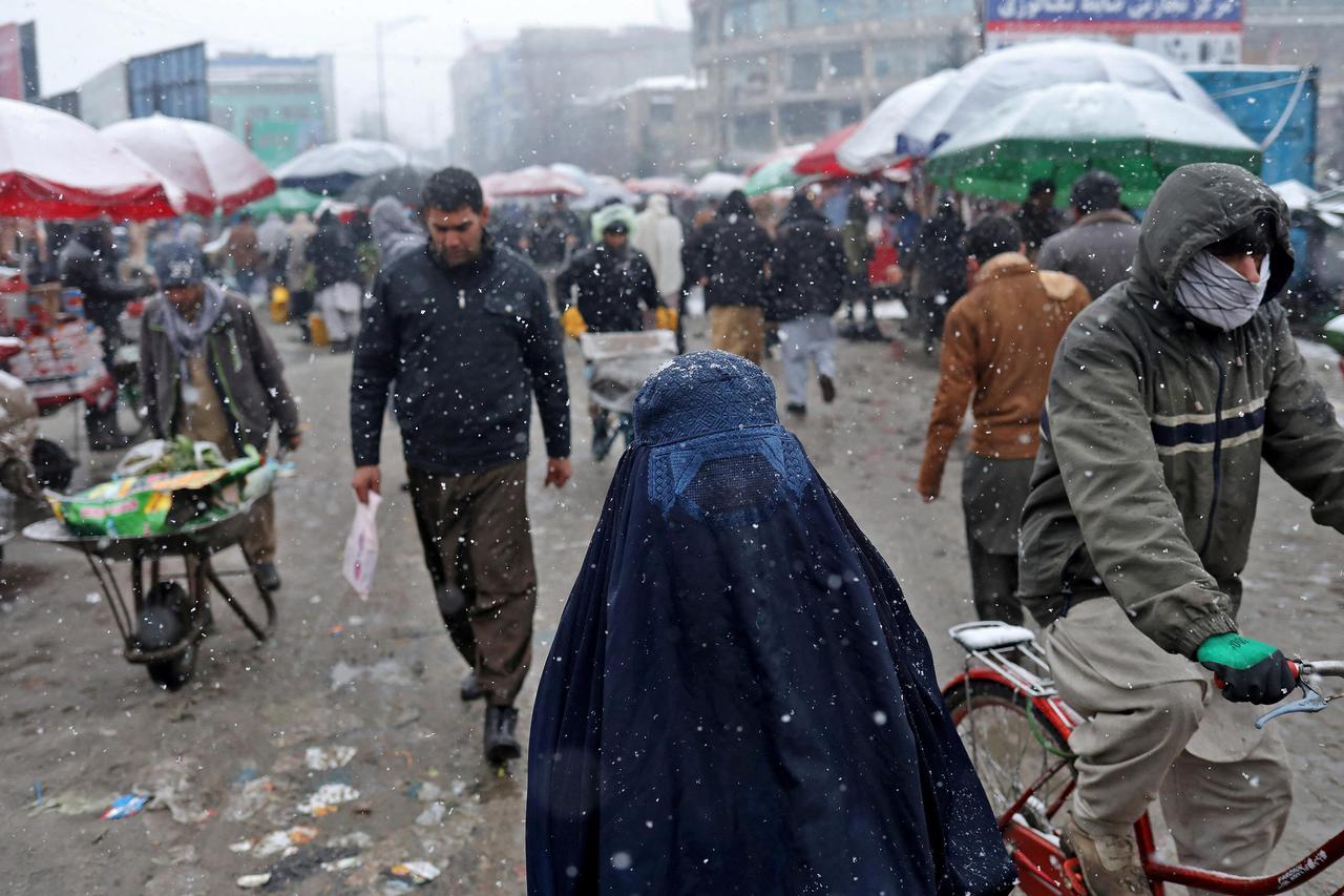An Afghan woman walks on the street during a snowfall in Kabul