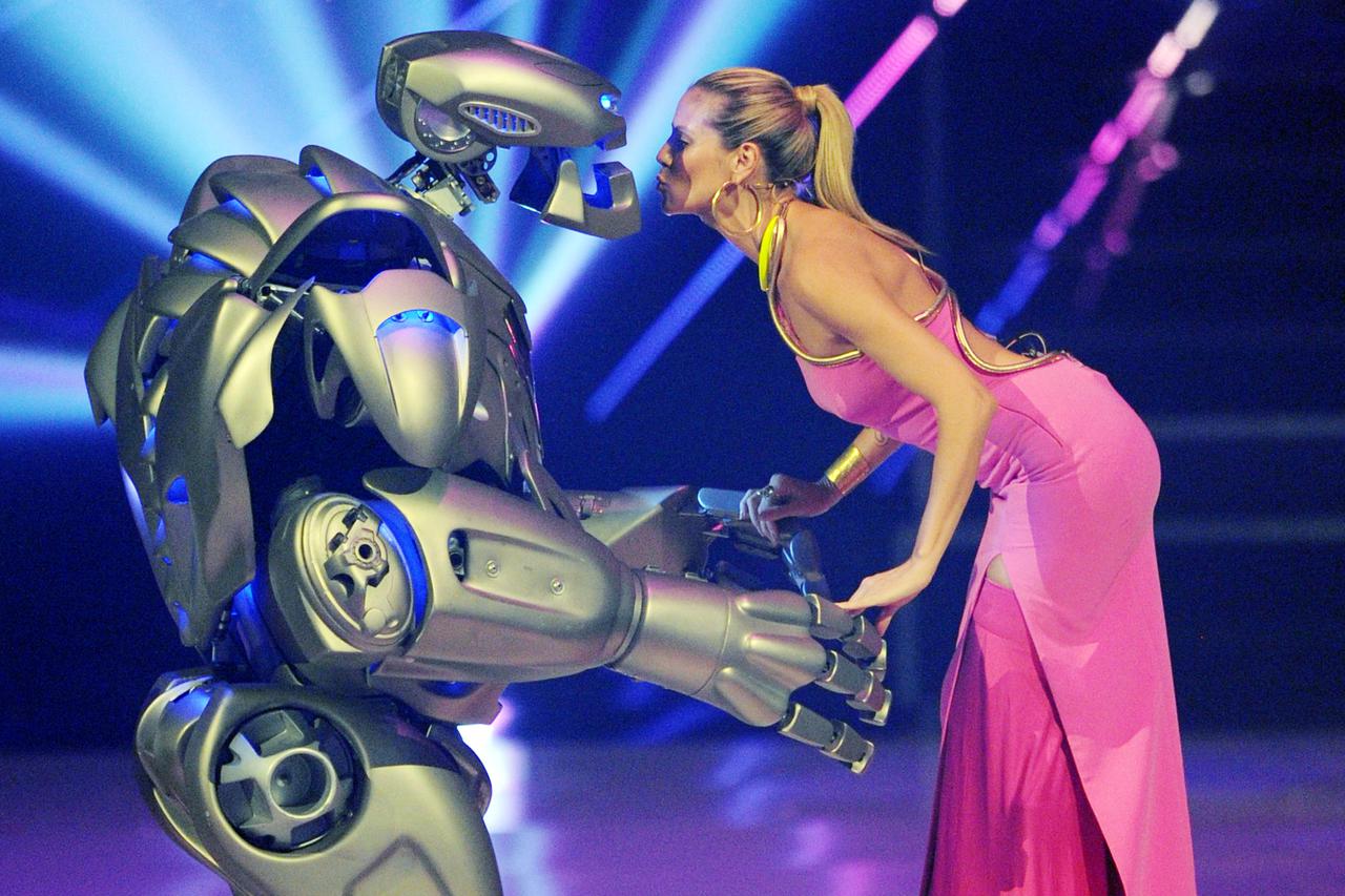 Jury member and casting show host Heidi Klum (R) stands on stage with an extra dressed in a robot costume during the final show of the German television model casting show 'Germany's Next Topmodel' at the SAP-Arena in Mannheim, Germany, 30 May 2013. Photo