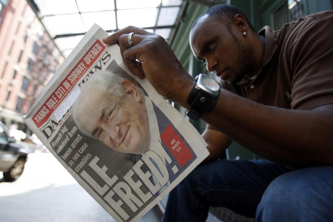'A man reads a paper with Dominique Strauss-Kahn on the front cover as media gather outside of the apartment where former IMF chief Dominique Strauss-Kahn is staying in New York on July 2, 2011. Strau