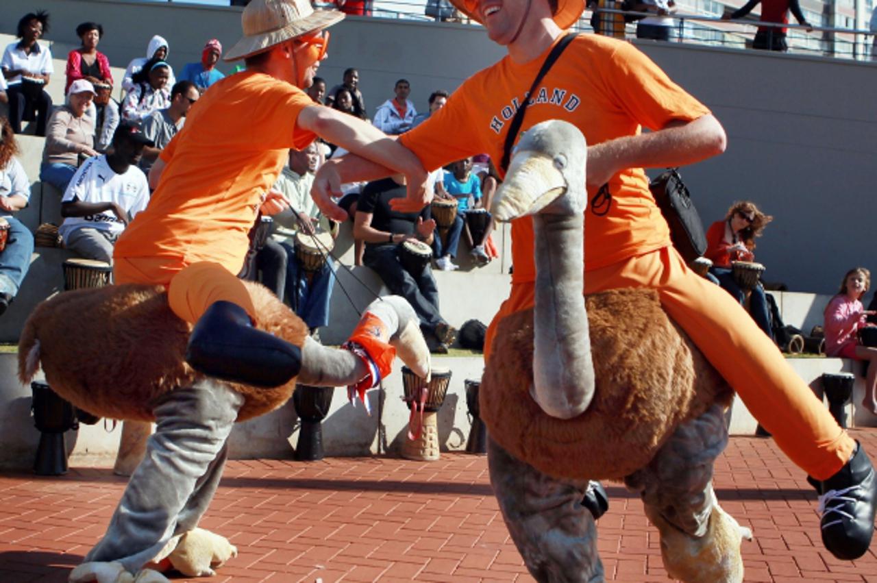 'Supporters (R) of the Netherlands football team dressed in ostrich outfits dance to a drum session on Durban\'s North Pier beach prior to the 2010 World Cup round of 16 match between the Netherlands 
