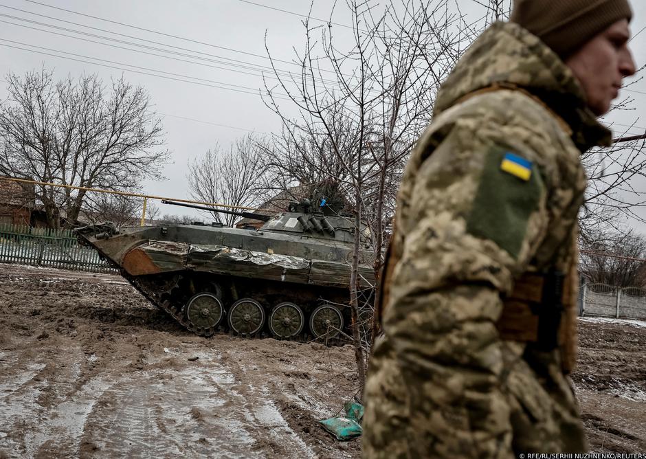 A Ukrainian service member walks near a BMP-2 infantry fighting vehicle on a frontline near the town of Soledar