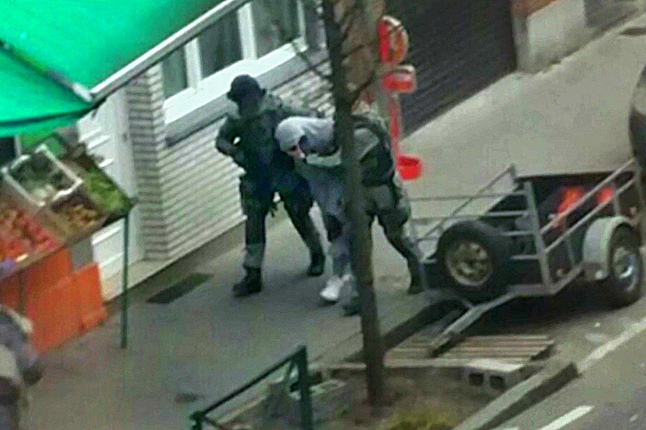 A suspect is apprehended by armed Belgian police in Molenbeek, near Brussels, Belgium, in this still image taken from video shot on March 18, 2016. Belgian-born Salah Abdeslam, one of the main suspects from November's Paris attacks, was arrested after a s