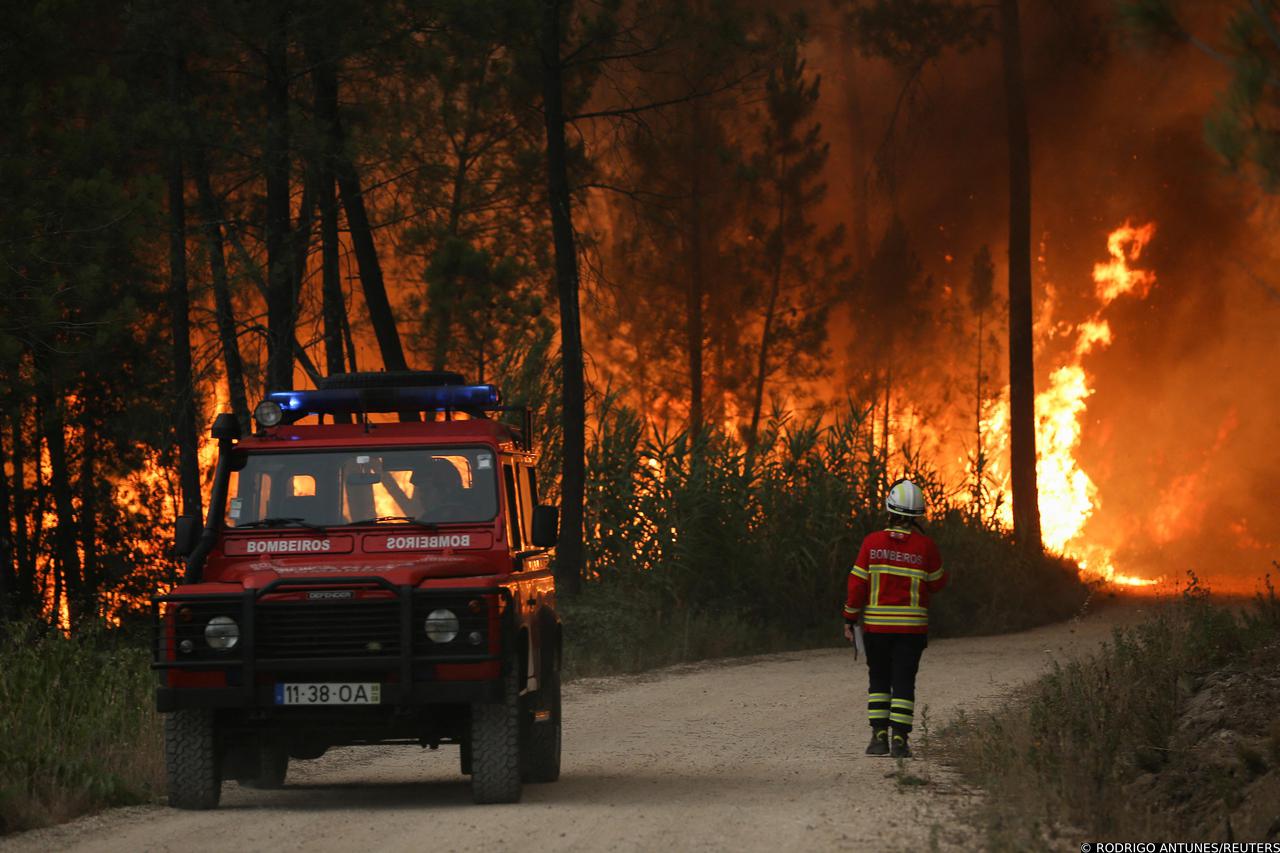 A firefighter walks near a wildfire in Ourem