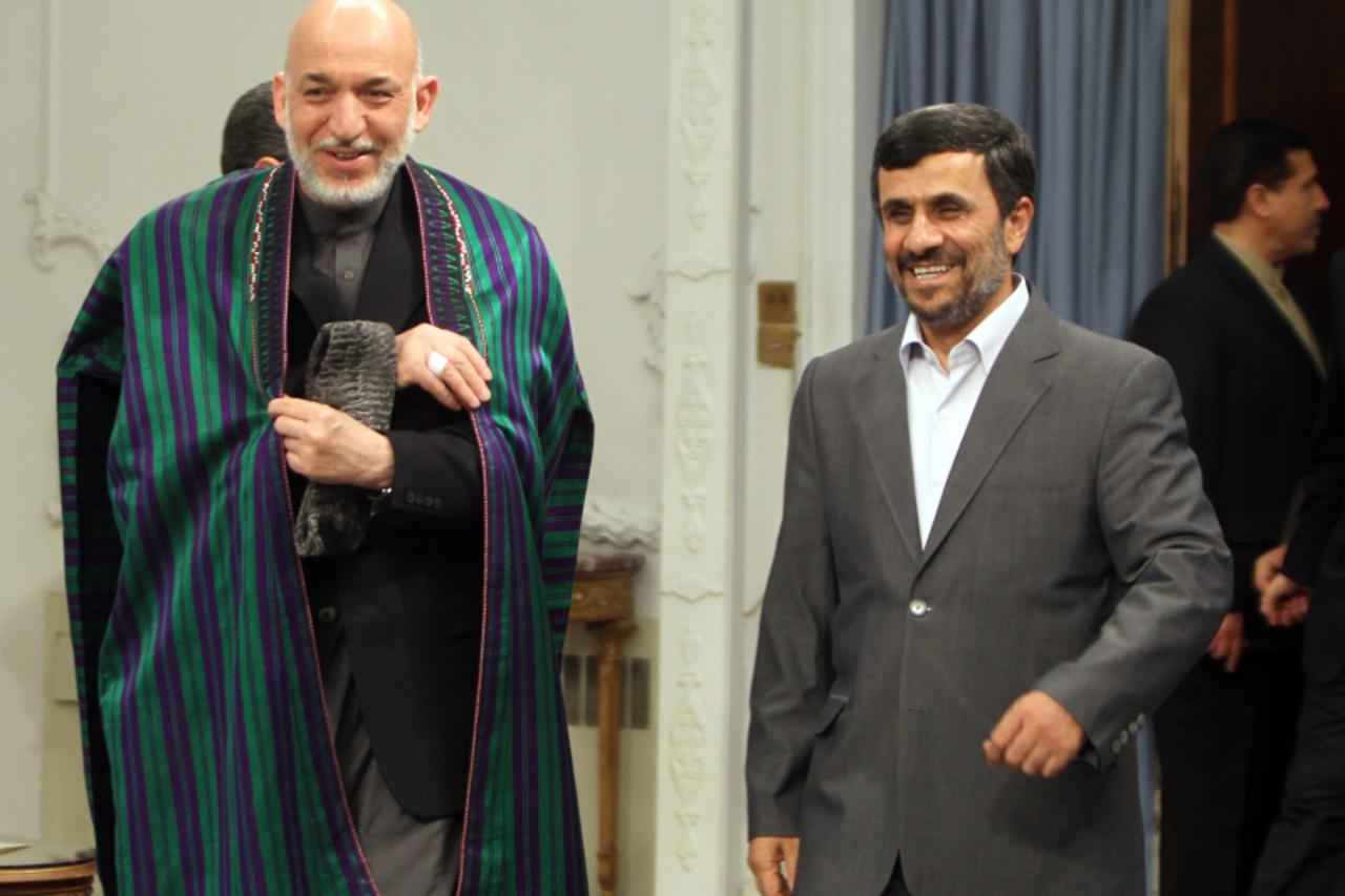 'Iranian President Mahmoud Ahmadinejad (R) greets his Afghan counterpart Hamid Karzai upon his arrival in Tehran on March 26, 2011, to attend celebrations for the Persian new year of Noruz on March 27
