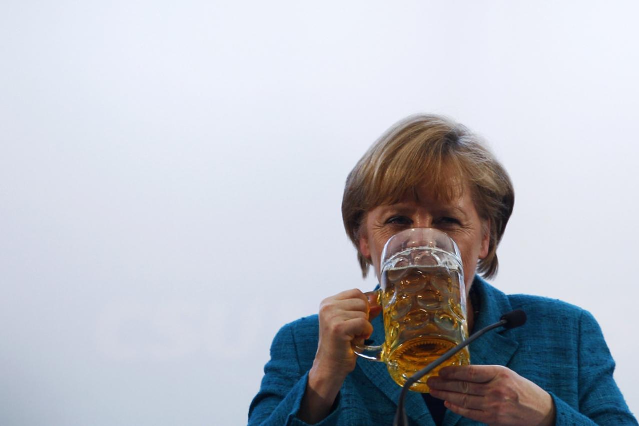 'German Chancellor and head of the Christian Democratic Union (CDU) Angela Merkel drinks a beer after her speech in a beer tent in Munich May 15, 2013. REUTERS/Michaela Rehle (GERMANY - Tags: POLITICS