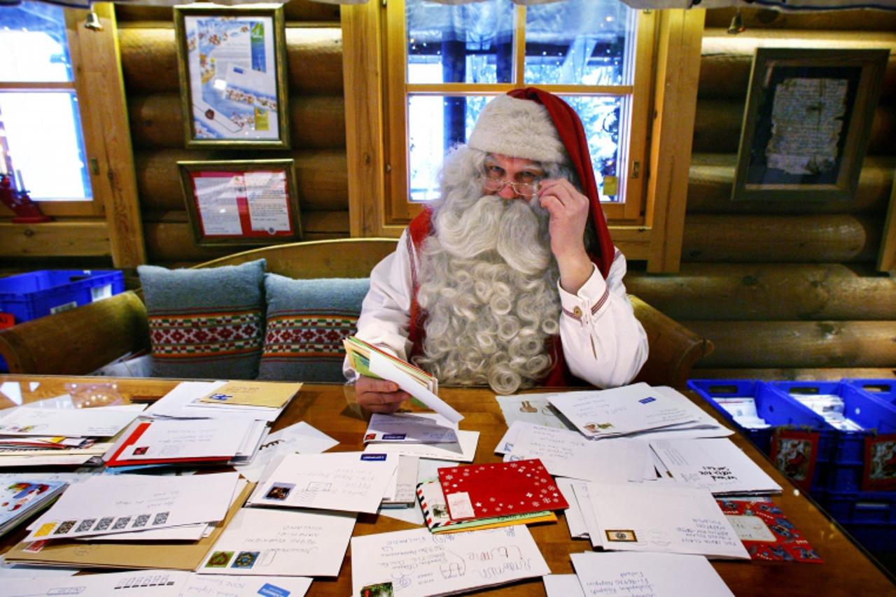 'A man dressed as Santa Claus looks over some of the thousands of letters received at the Santa Claus Office located on the Arctic Circle near Rovaniemi November 26, 2009. REUTERS/Bob Strong  (FINLAND