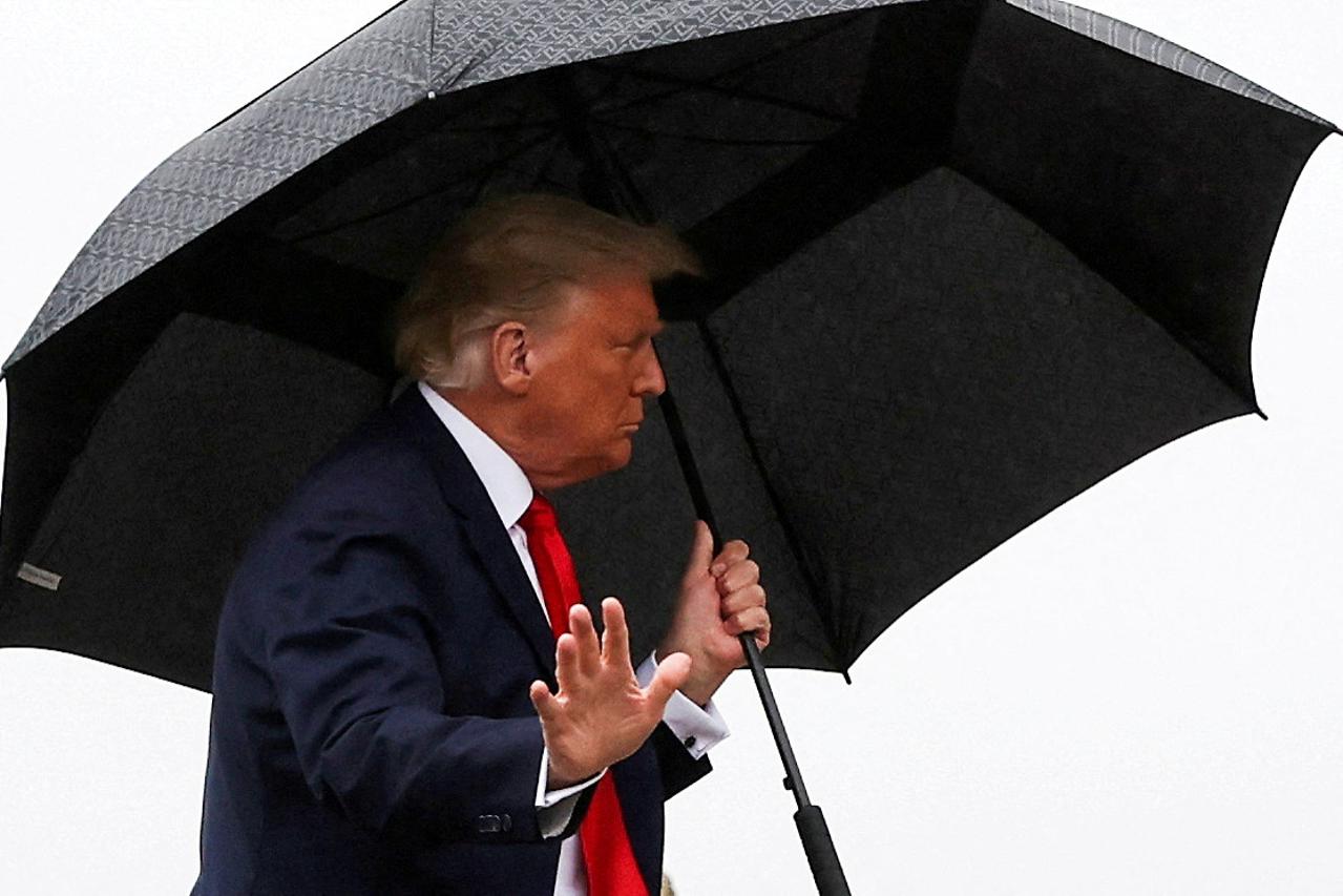 FILE PHOTO: U.S. President Donald Trump walks without a mask and carries an umbrella while boarding Air Force One as he departs Washington