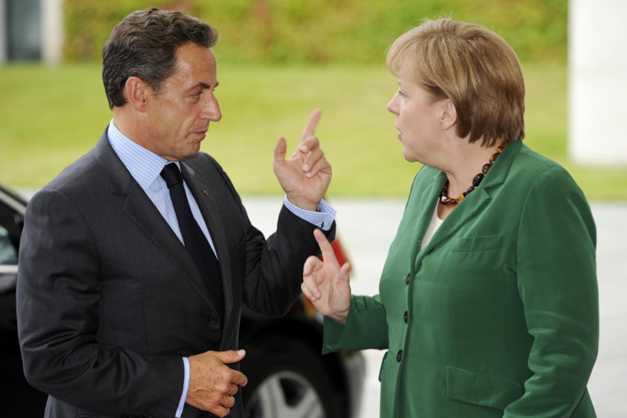 'German Chancellor Angela Merkel greets French President Nicolas Sarkozy on July 20, 2011 in the courtyard of the Chancellory in Berlin, prior to talks one day ahead of a pivotal summit of heads of st
