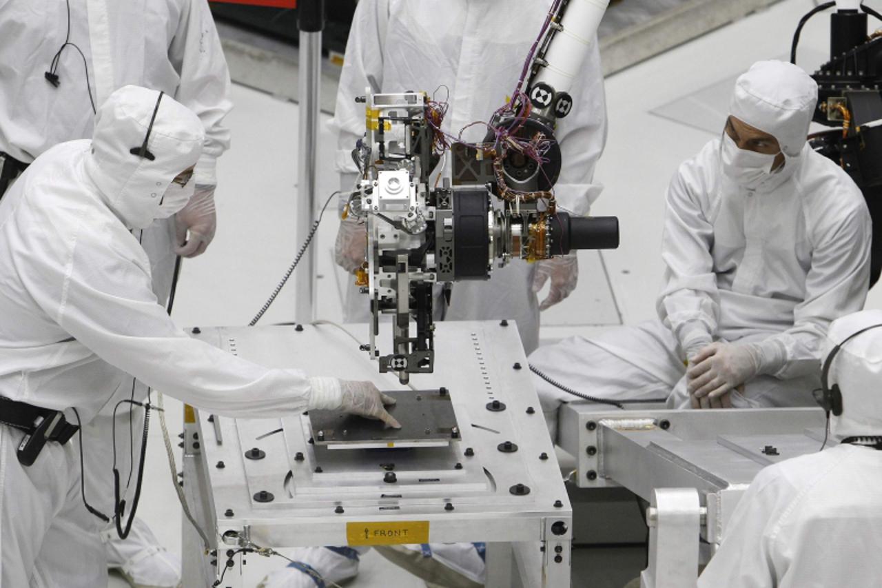 'Technicians monitor movement of the robotic arm of NASA\'s Mars Science Laboratory rover \'Curiosity\', where it is undergoing pre-flight tests, in the \'clean room\' of the spacecraft assembly facil