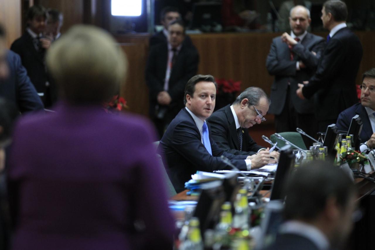 'Britain\'s Prime Minister David Cameron (C) looks at Germany\'s Chancellor Angela Merkel (L) at a European Union summit in Brussels December 9, 2011. EU leaders agreed stricter budget rules for the e