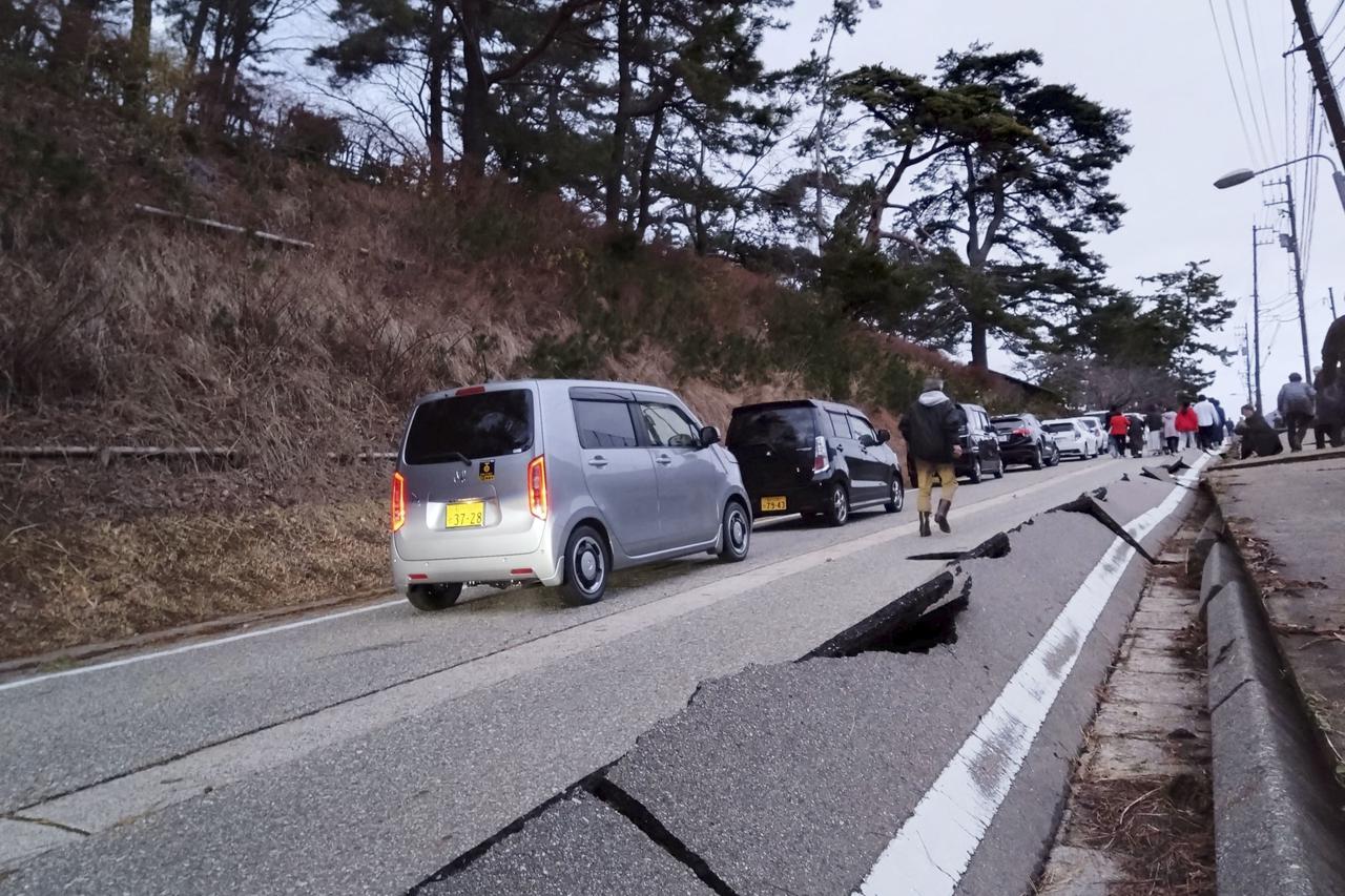 People walk along a road damaged by an earthquake, in Wajima