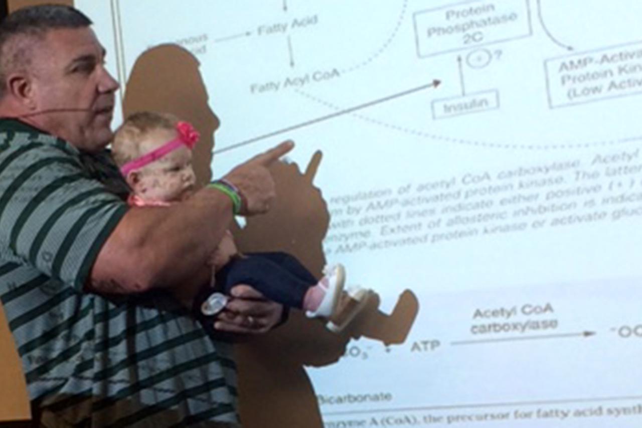 Profesor predaje držeći dijete studenta