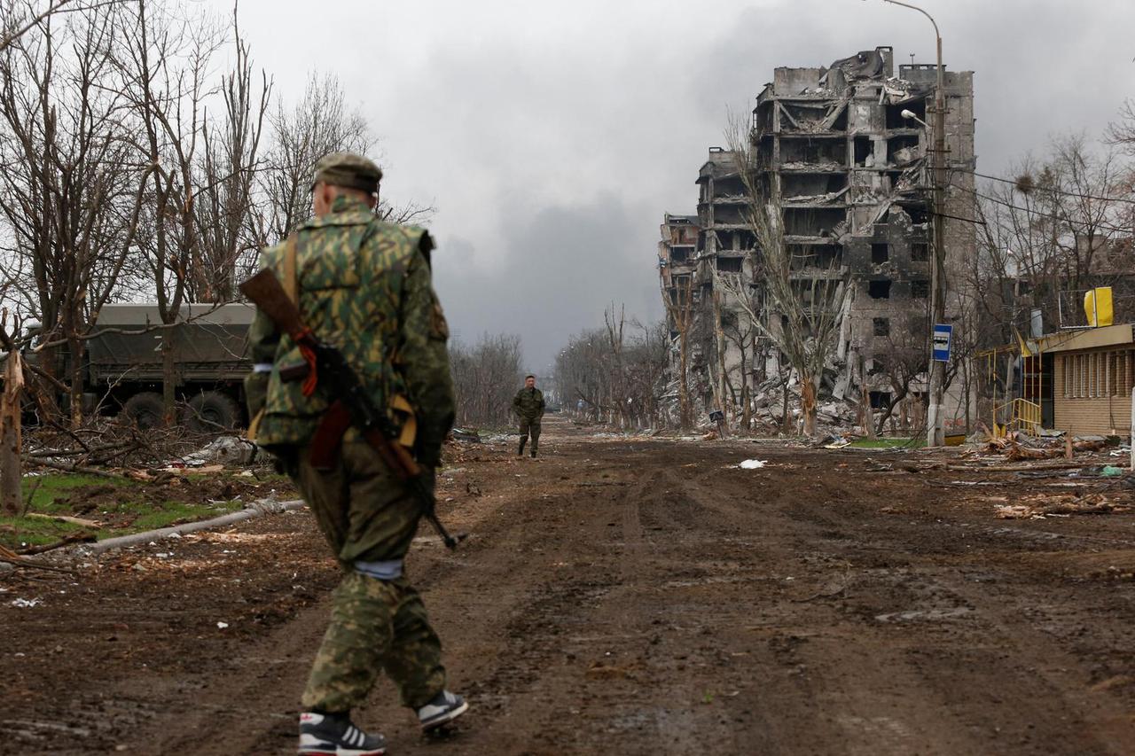 Service members of pro-Russian troops walk in the street during fighting in Mariupol