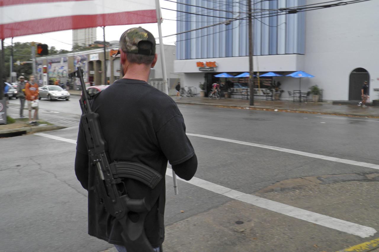 A pro-gun advocate walks down the street outside the University of Texas ahead of a 'mock mass shooting' event where they used cardboard cut-outs rifles, the simulated bangs of bullets on bullhorns and doused fake victims with fake blood, in Austin, Texas