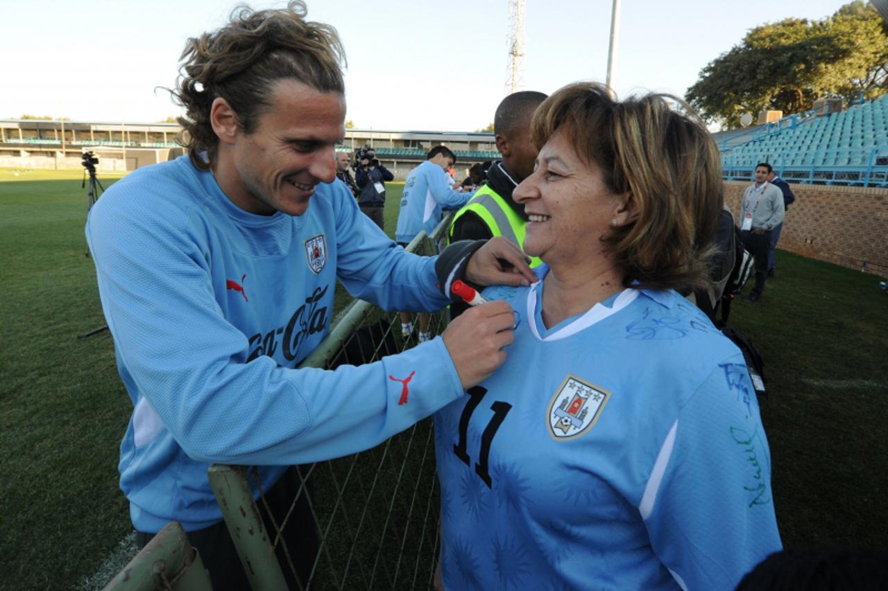 'Uruguay\'s striker Diego Forlan (L) sign an autograph on the Uruguay jersey worn by Premier of the Northern Cape province Hazel Jenkins during a training session at GWK Park stadium in Kimberley on J
