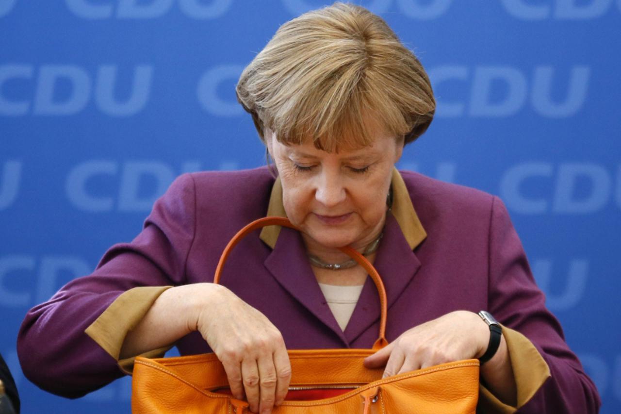 'Christian Democratic Union (CDU) party leader and Chancellor Angela Merkel looks into her bag at  a party board meeting in Berlin, May 14, 2012. Chancellor Angela Merkel\'s conservatives suffered a c