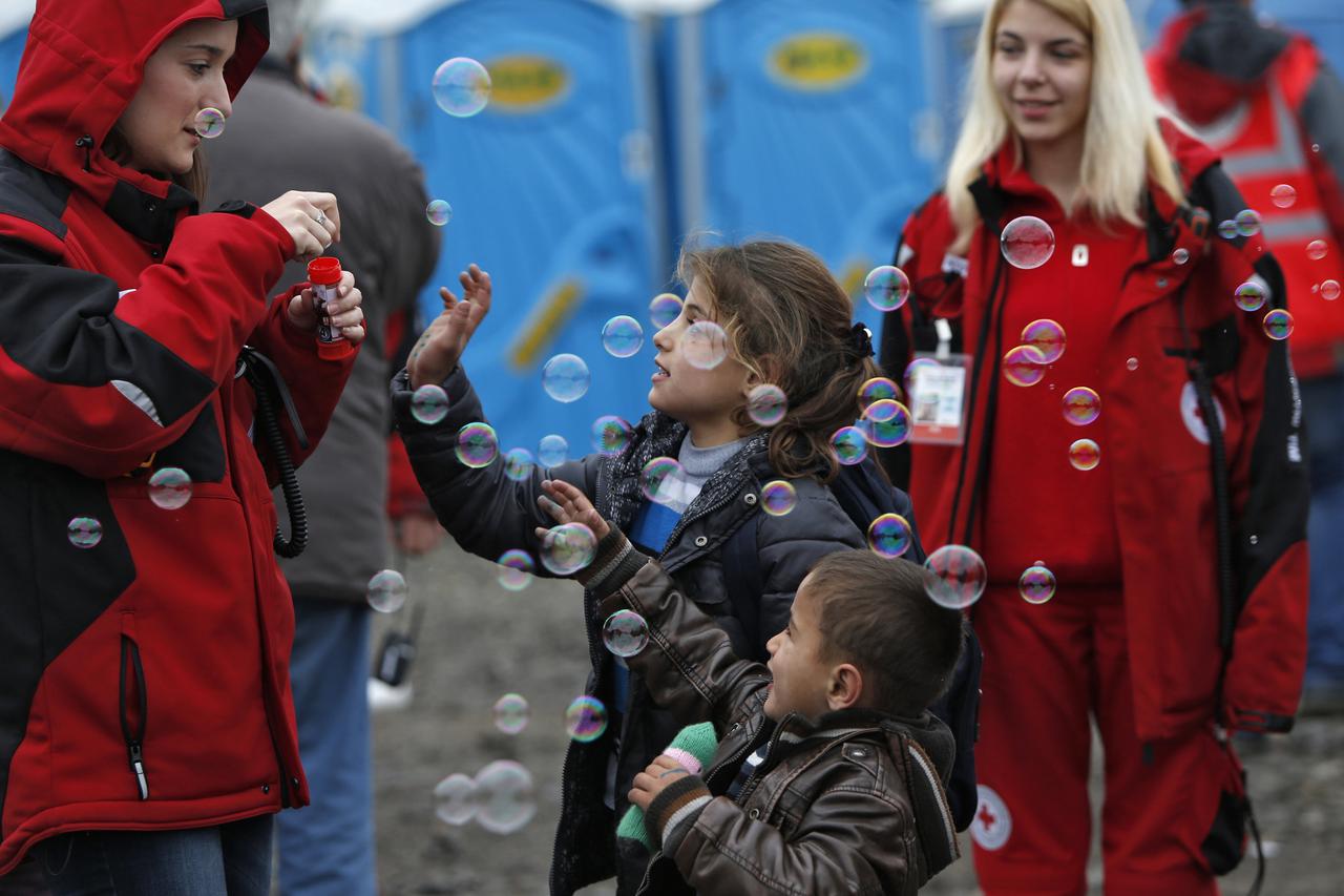 Children play with bubbles blown by volunteers as migrants and refugees are registered by the authorities before continuing their train journey to western Europe at a refugee transit camp in Slavonski Brod, Croatia, February 10, 2016. REUTERS/Darrin Zammi