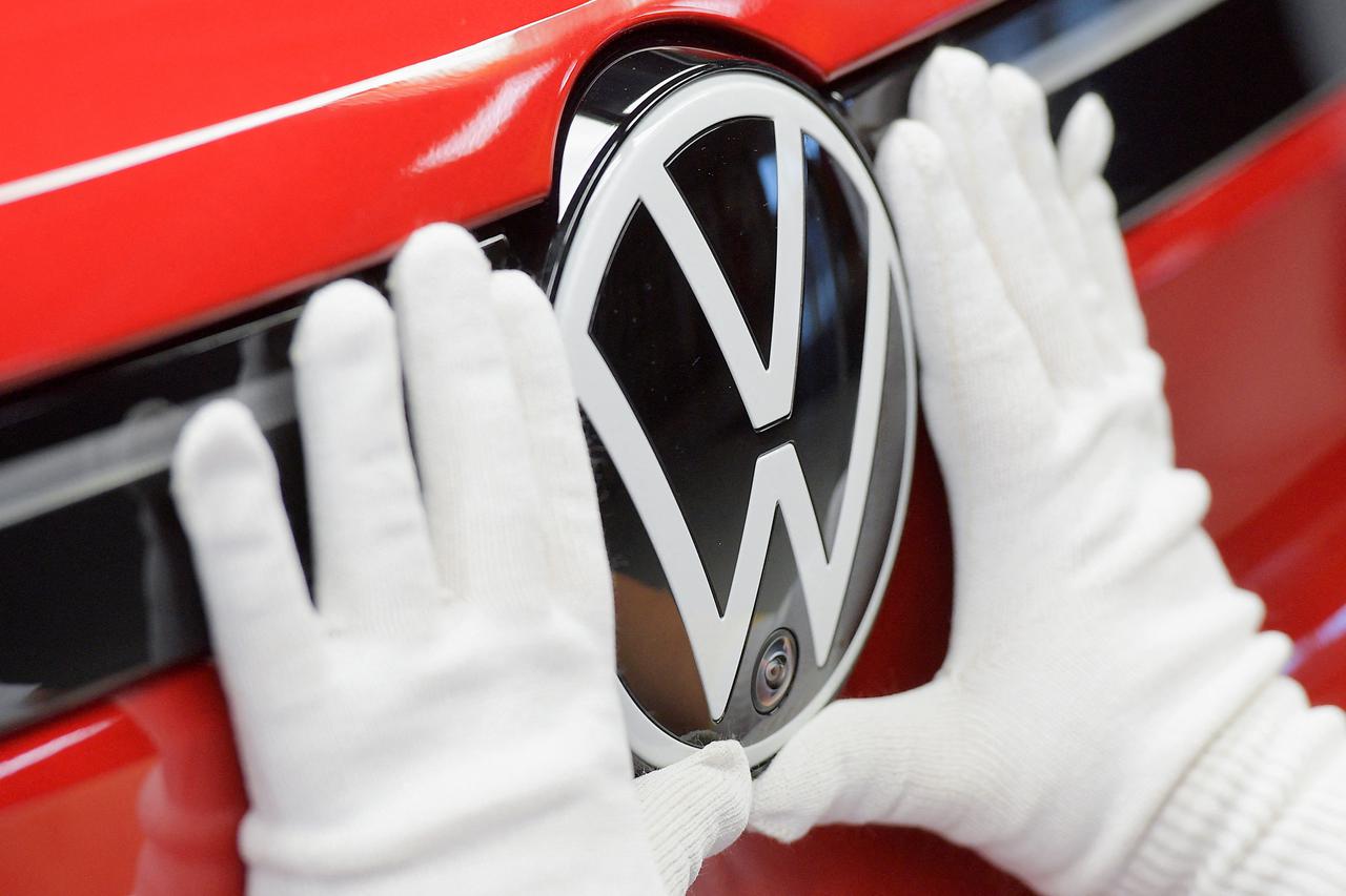 FILE PHOTO: A technician attaches a Volkswagen logo to a car, at the production line for electric car models of the Volkswagen Group, in Zwickau