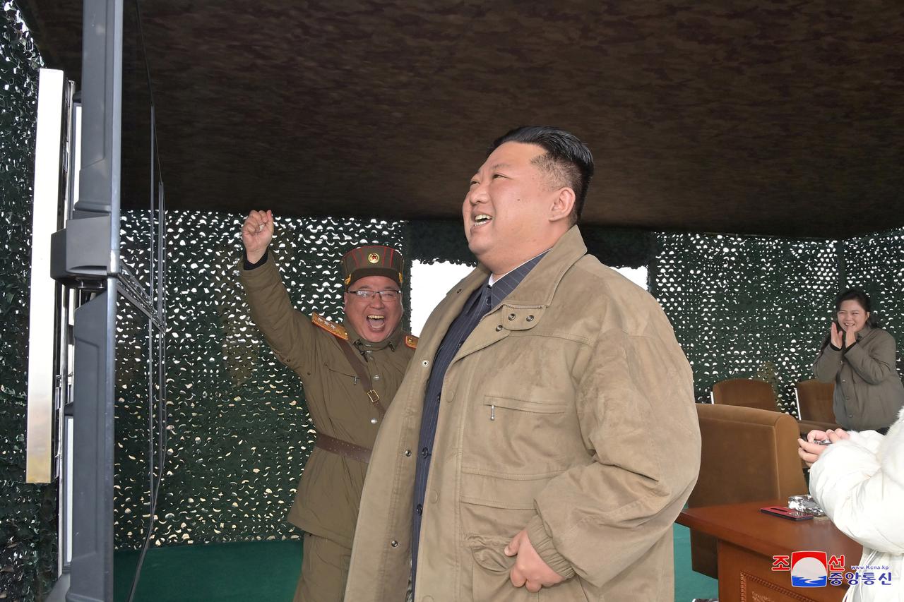 North Korean leader Kim Jong Un, with his wife Ri Sol Ju, reacts on the day of the launch of an ICBM in this undated photo released by KCNA
